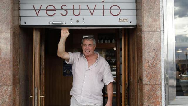 Un hombre saluda desde la puerta de la pizzería Vesuvio, en Gijón