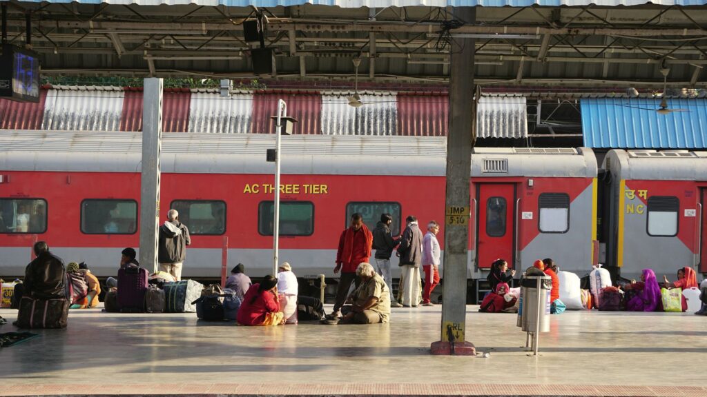 Viajeros esperando en el andén junto a un tren rojo