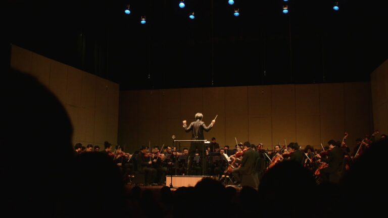 Director dirigiendo una orquesta en un auditorio